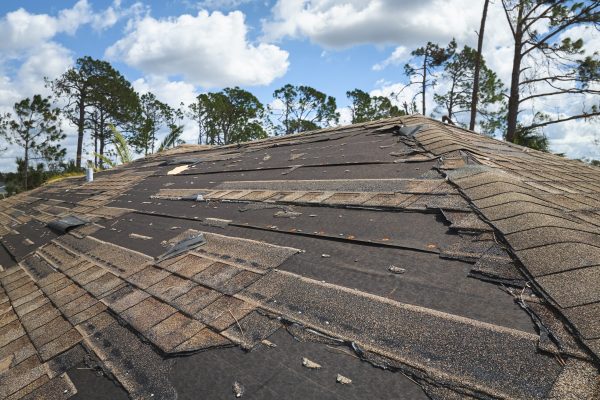 Damaged house roof with missing shingles after hurricane Ian in Florida. Consequences of natural disaster.